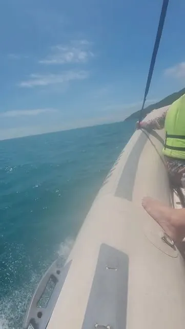 Passageiro com colete salva-vidas na lateral da lancha em mar aberto
